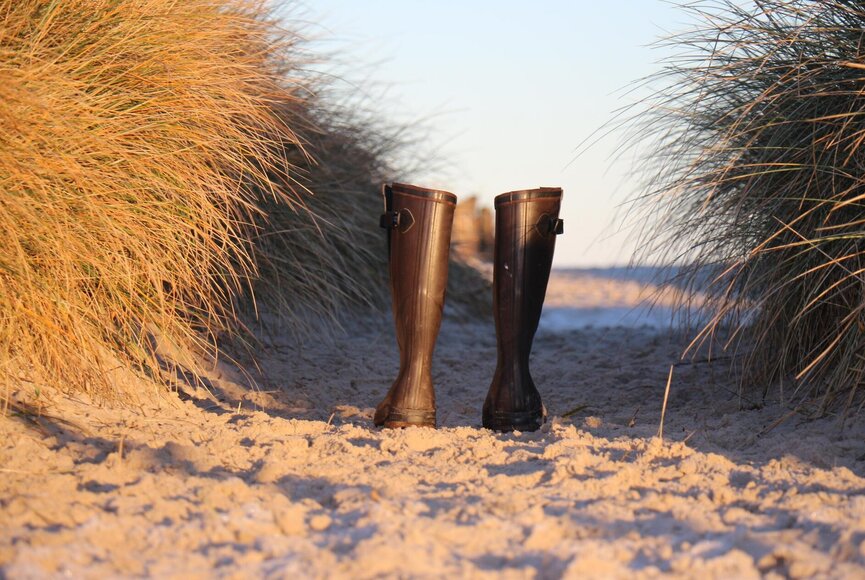 ein Paar Gummistiefel in den Dünen 