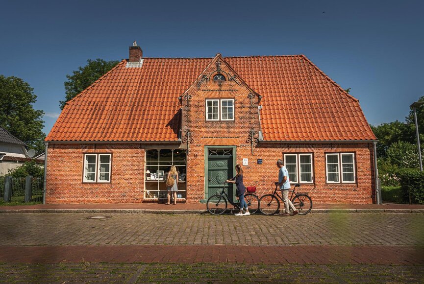 Paar mit Fahrrädern vor dem Haus Peters mit rotem Backstein und rotem Dach