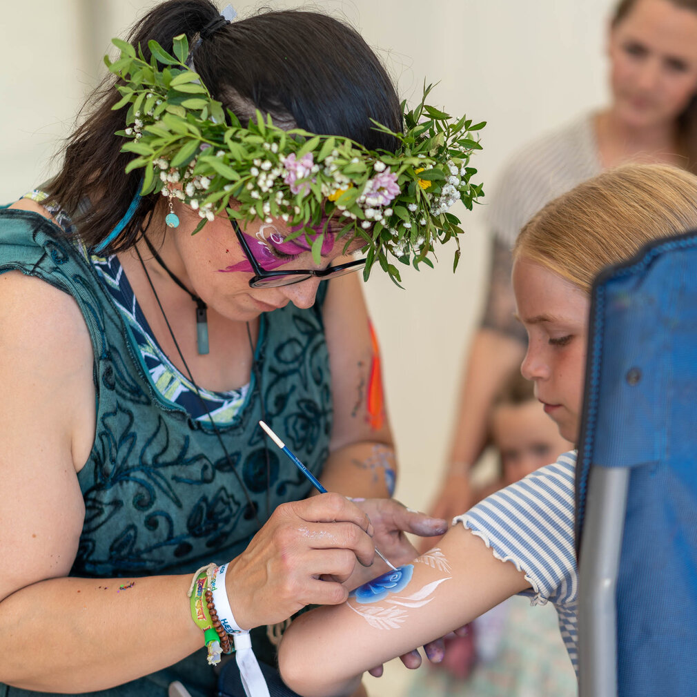 Ein Mädchen bekommt ein schöne Blume auf den Arm gemalt