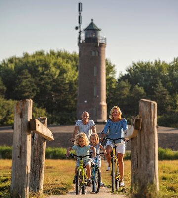 Familie auf Radtour vor dem Böhler Leuchtturm