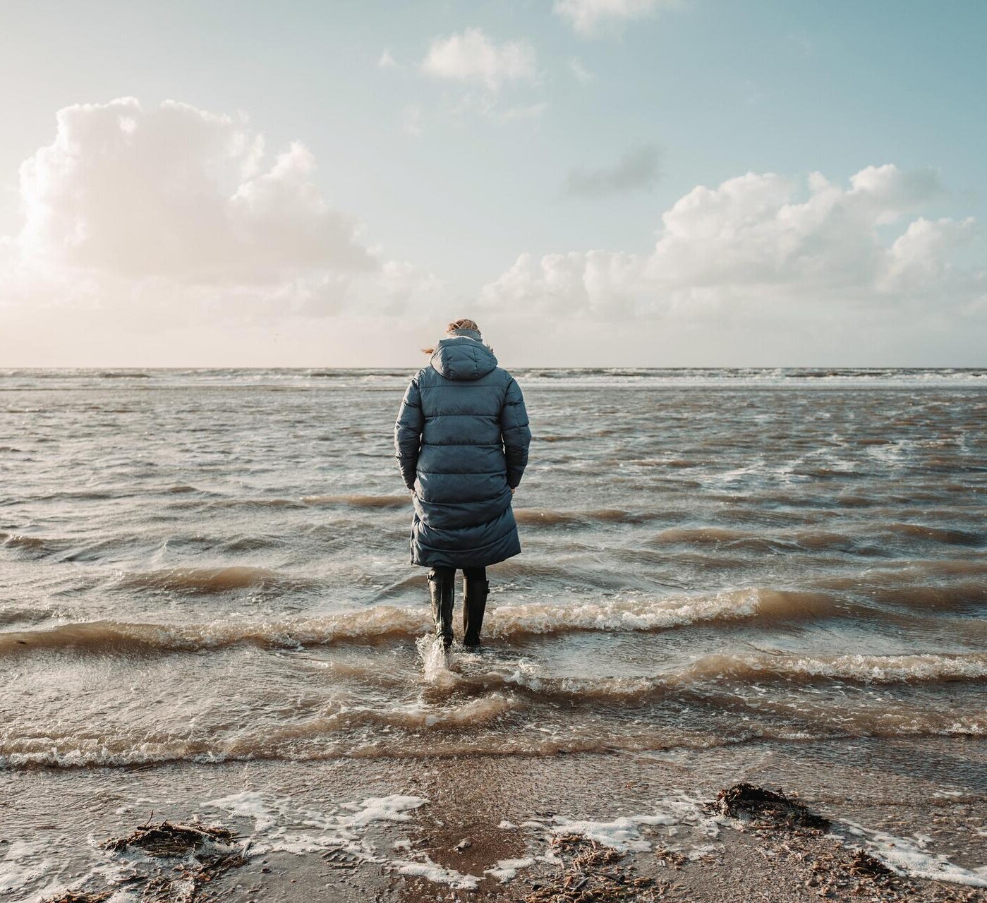 Dame mit Gummistiefeln bei Flut im Wasser