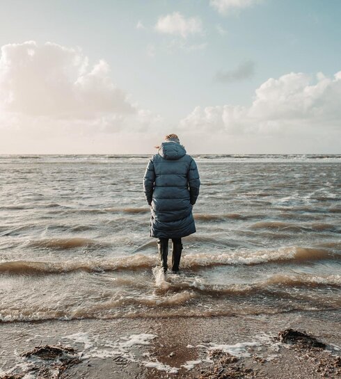 dick angezogene Frau mit den Gummistiefeln im Wasser