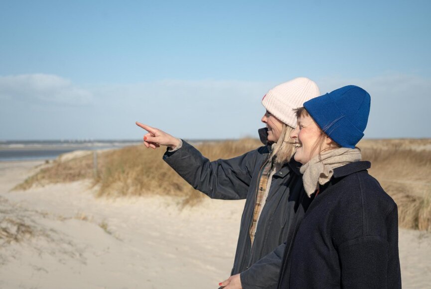 Zwei Frauen am Strand zeigen auf etwas