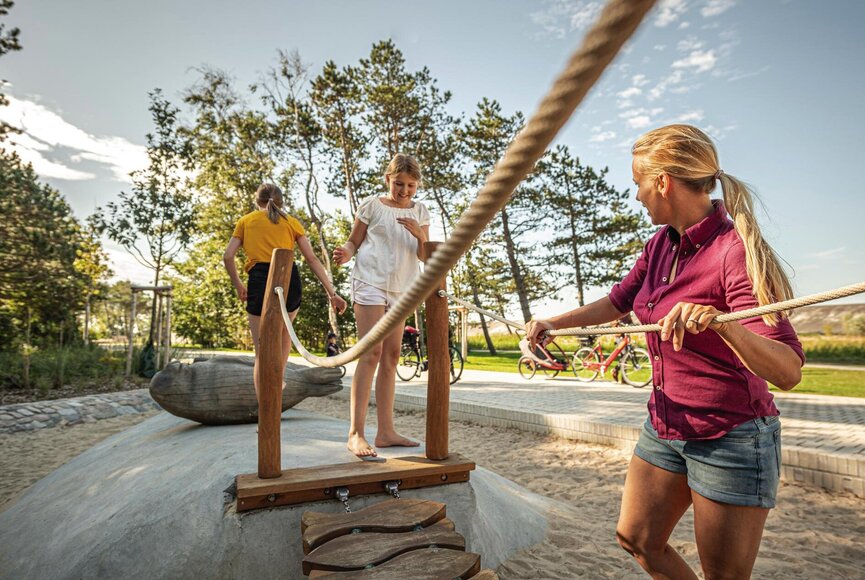 Familie spielt auf Geräten der Erlebnis-Promenade