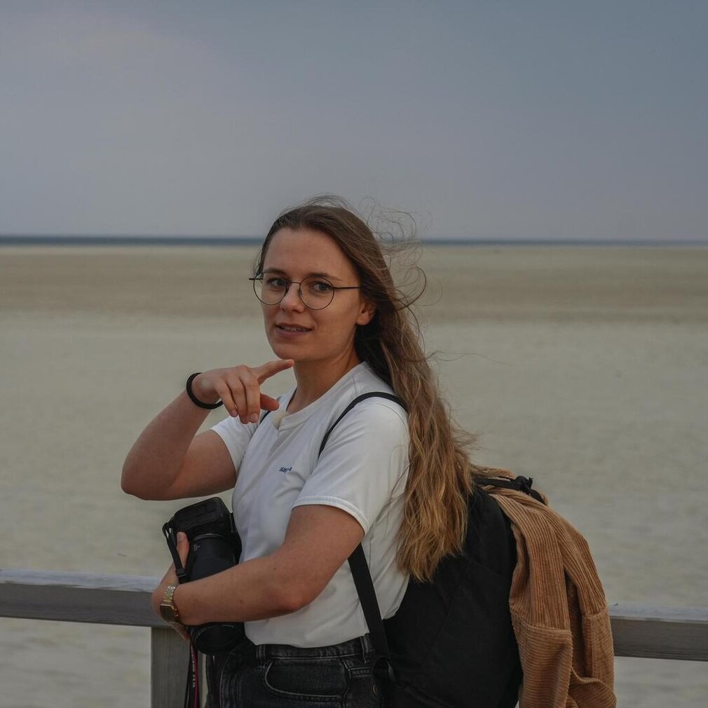 Marina steht auf der Seebrücke und zeigt mit dem Finger auf Dünen