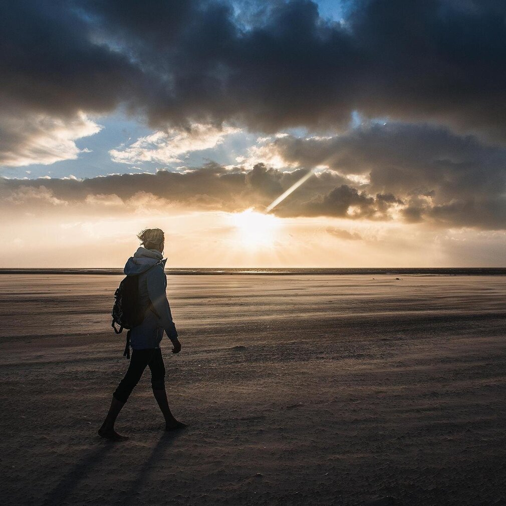 Person läuft alleine am Strand