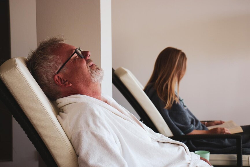Mann und Frau entspannen im Ruhebereich auf Liegen