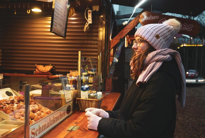 Eine Frau steht an einem Weihnachtsstand mit leckerem Weihnachtsgebäck