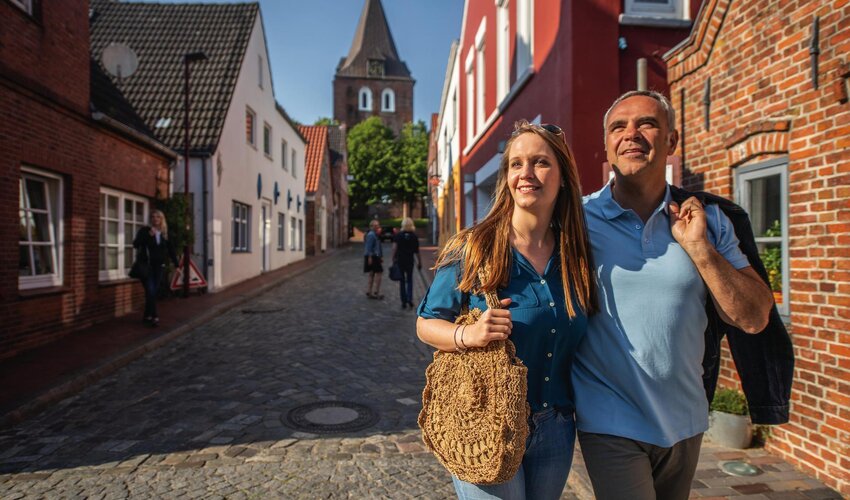 Paar Arm in Arm unterwegs in der Altstadt in Garding mit Kirchturm im Hintergrund