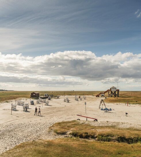 Vogelperspektive auf den Südstrand mit Pfahlbau, Strandkörben und Spielplatz
