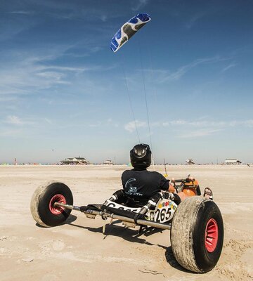 Kitebuggyfahrer beim Fahren über den weitern Strand bei Sonnenschein