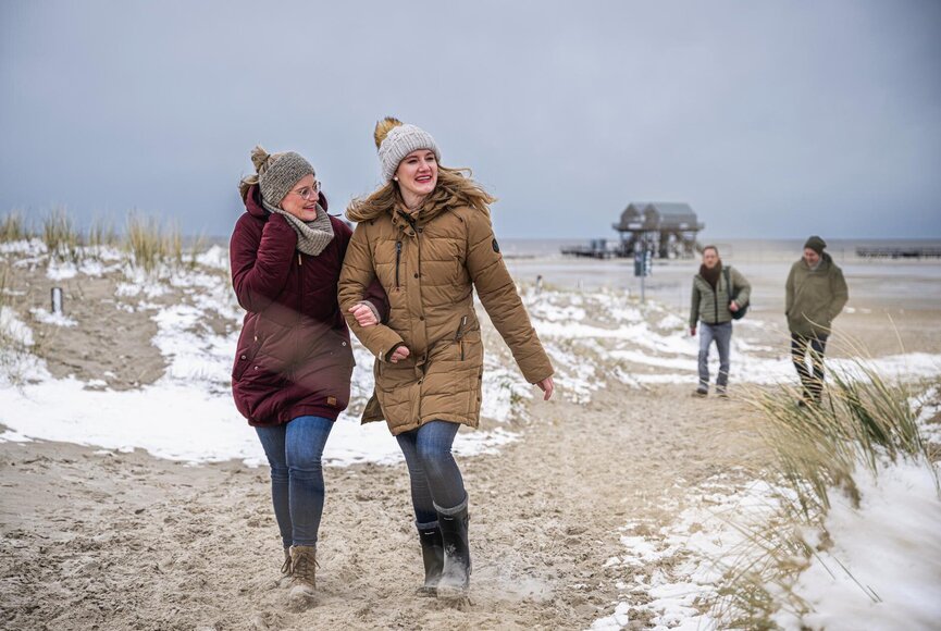 Freundinnen spazieren am Winterstrand