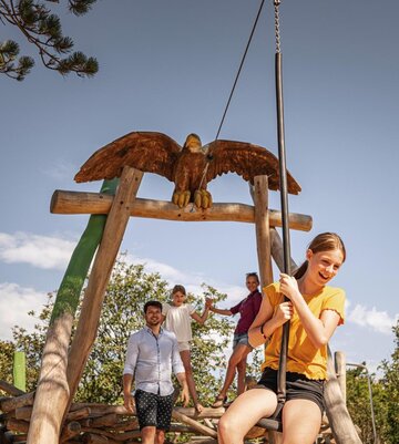 Familie beim Spielen auf der Seilbahn auf einem Spielplatz auf der Erlebnis-Promenade