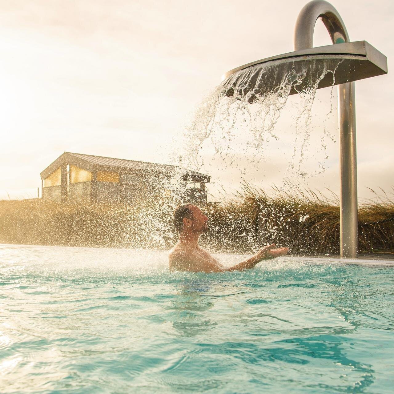 Mann im Außenbecken der Dünen-Therme unter der Schwalldusche