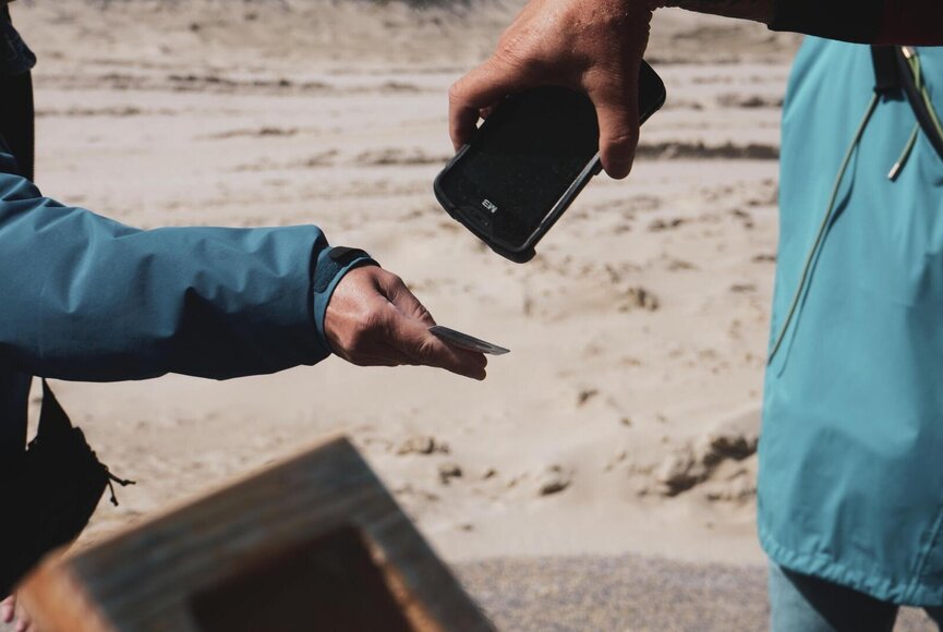Strandmitarbeiter scannt die Gästekarte eines Gastes ab
