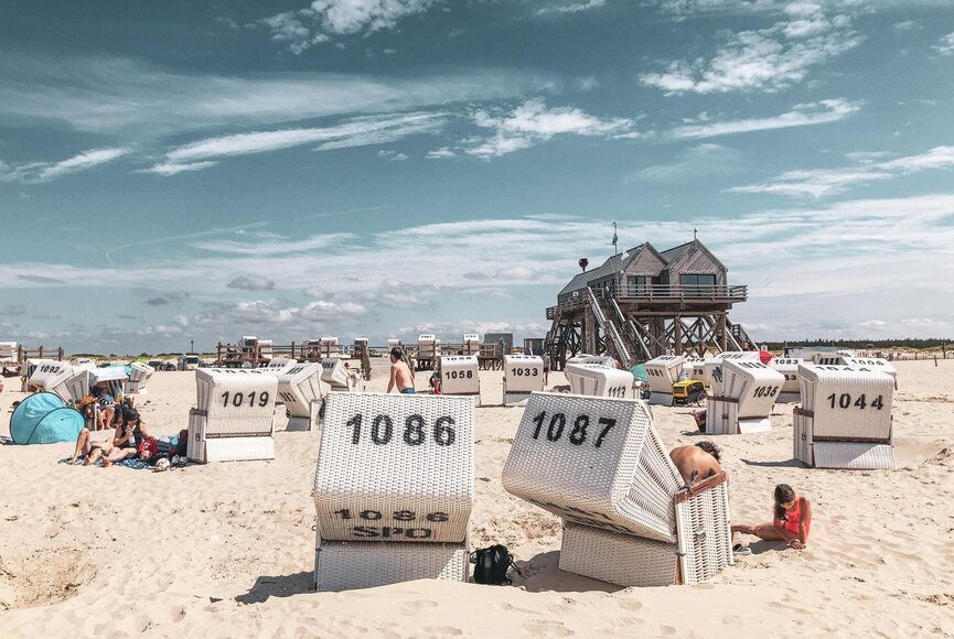 Warmer Sommertag in St. Peter-Ording, der Strand und Strandkörbe werden genutzt um sich zu sonnen und den Tag am Strand zu genießen