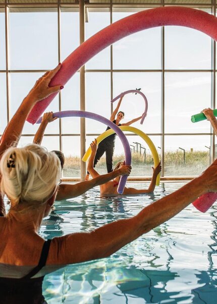 Sportgruppe mit Poolnudeln im Bewegugsbad