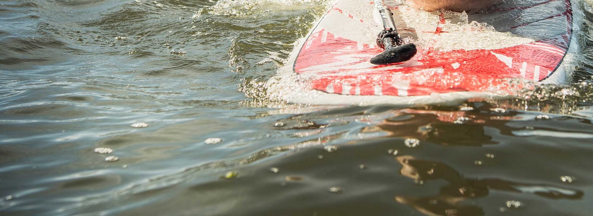 Mann liegt bäuchlings auf einem Surfbrett und schwimmt auf der Nordsee