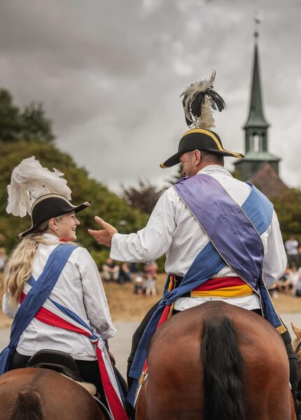 Reiter in festlicher Kleidung auf dem Marktplatz