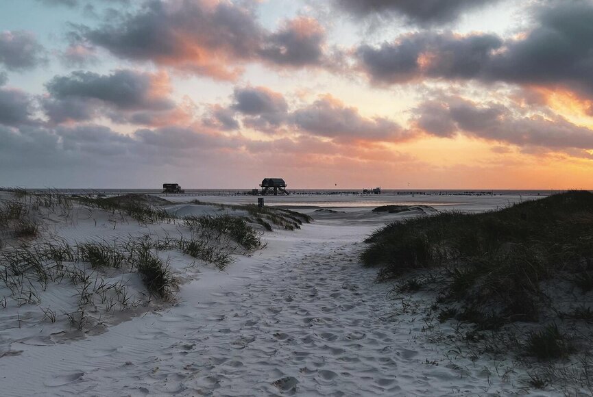 Sonnenuntergang am Strand in Ording mit Pfahlbau im Hintergrund