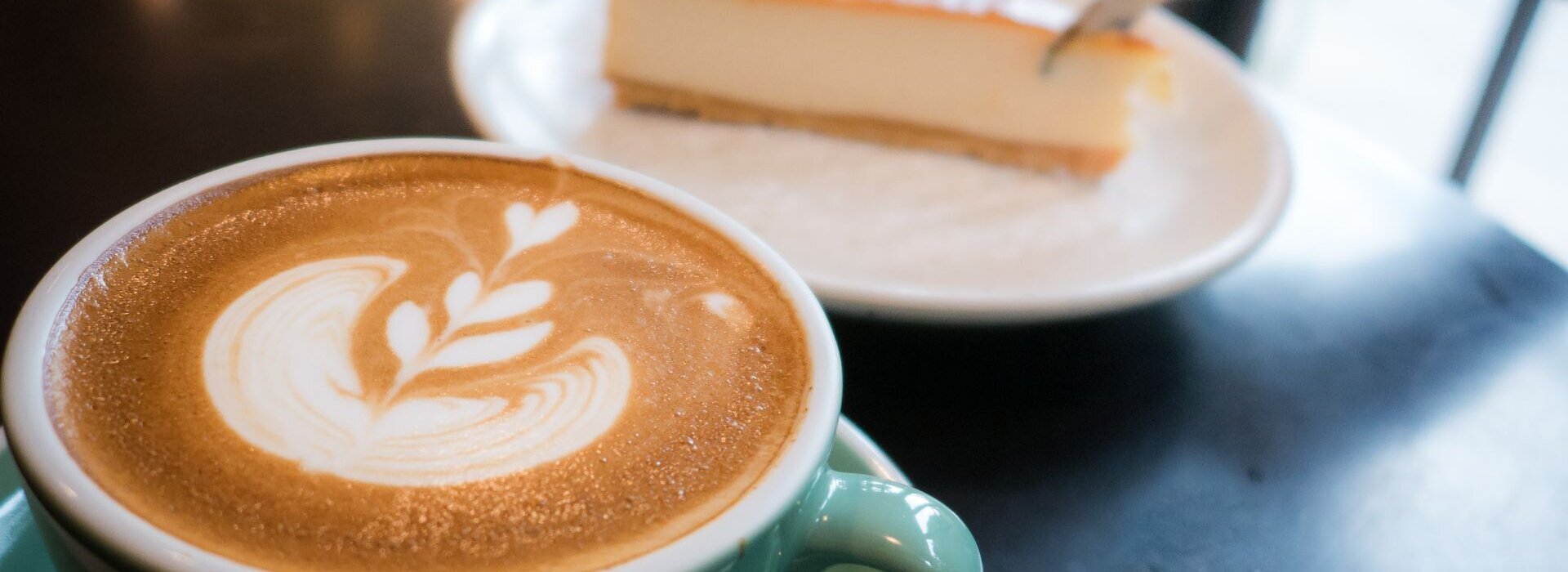 eine Tasse Cappuccino und ein Stück Käsekuchen