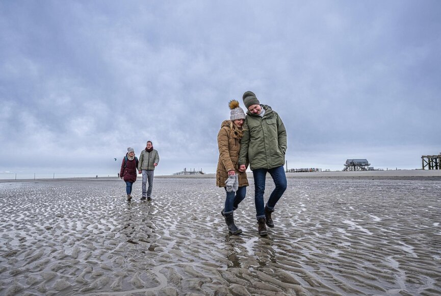 zwei Pärchen spazieren am grauen Winterstrand