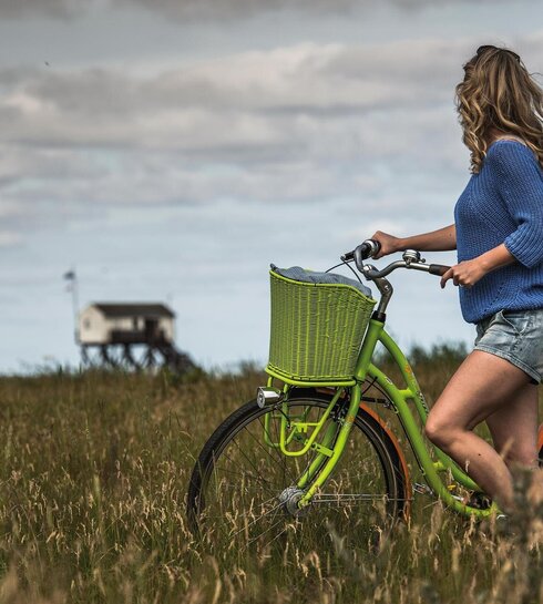 sympathische Dame auf einem grünen Fahrrad vor der Strandaufsicht am Südstrand