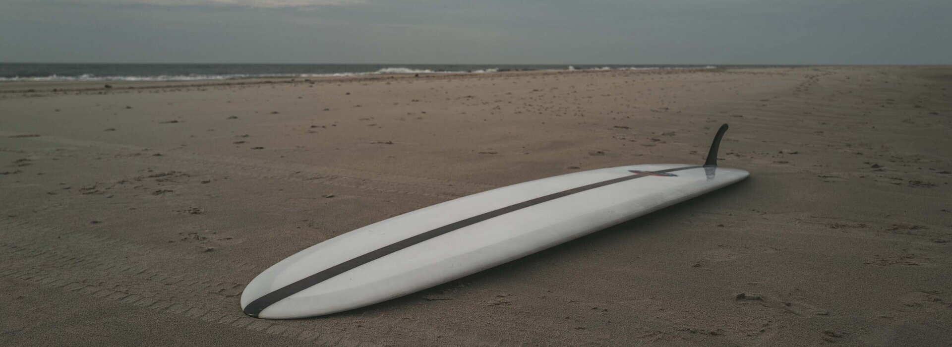 weißes Surfbrett liegt im Sand