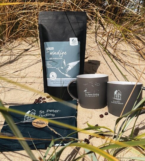 SPO Kaffee, Kaffeetassen und ein Geschirrtuch mit Pfahlbau Aufdruck in den Dünen