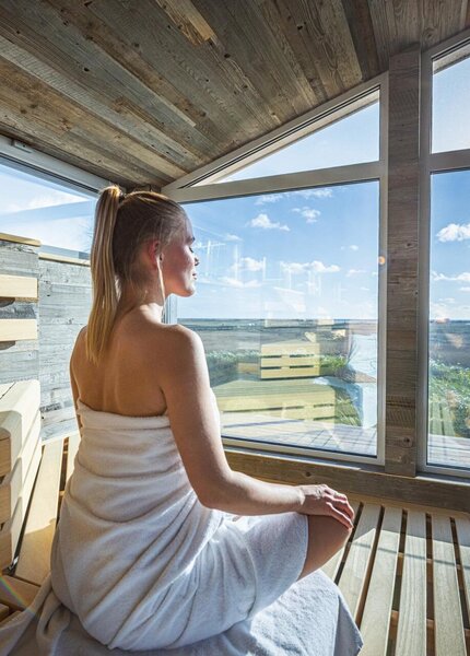 Frau entspannt in der Sauna mit Blick auf die Dünen