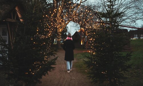 Eine junge Frau spaziert durch einen Tunnel mit vielen funkelnden Lichtern