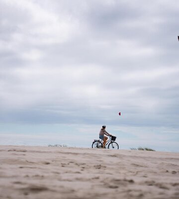 Person fährt am Strand Fahrrad