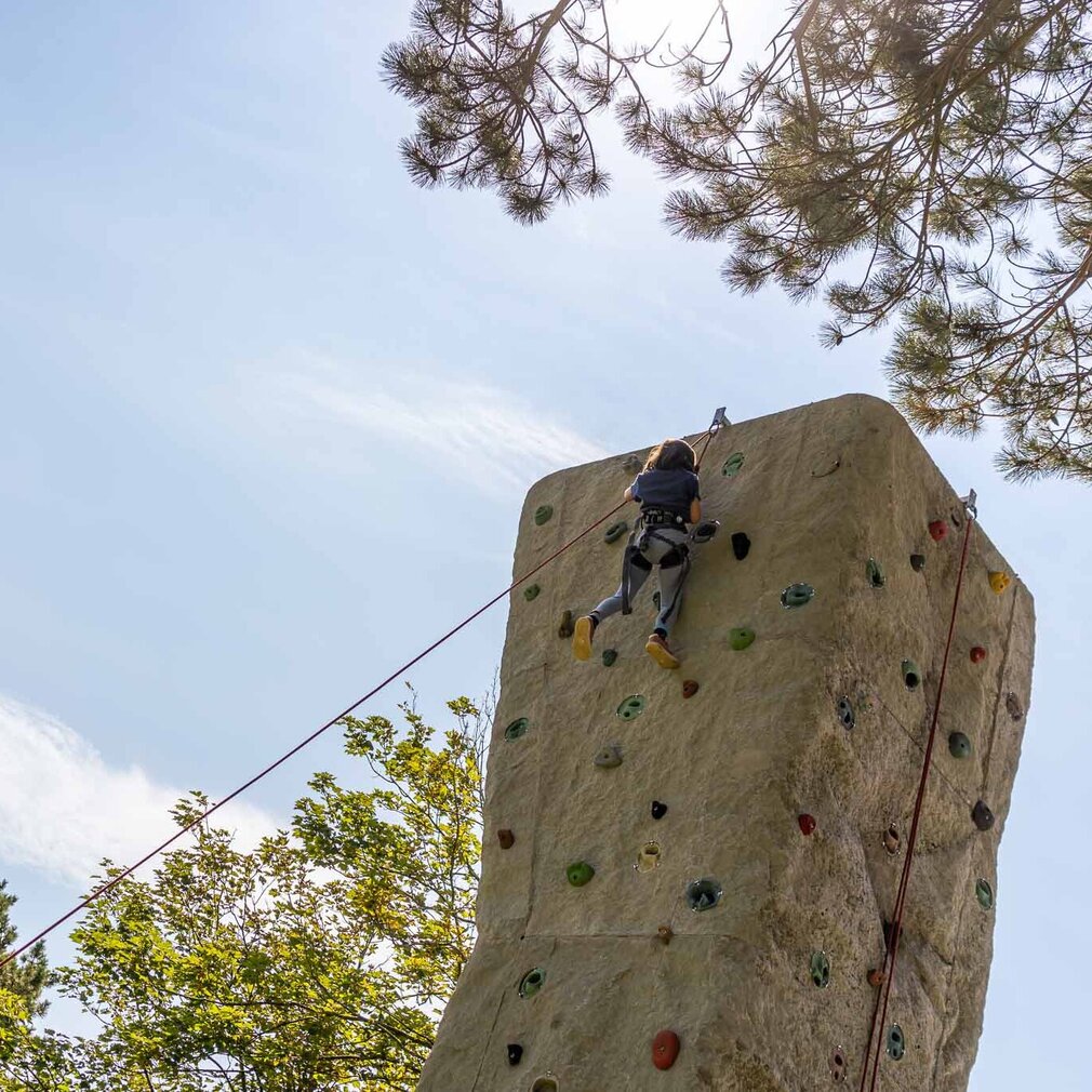 ein Junge klettert den großen Kletterfelsen hinauf