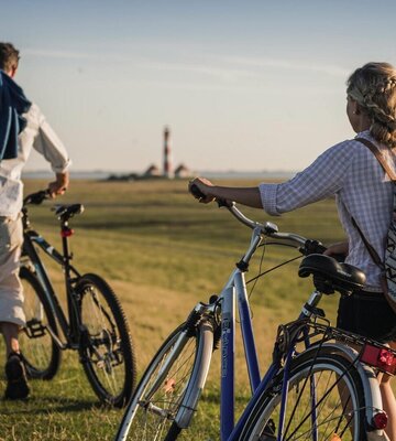Paar mit Fahrrädern vor dem Westerhever Leuchtturm