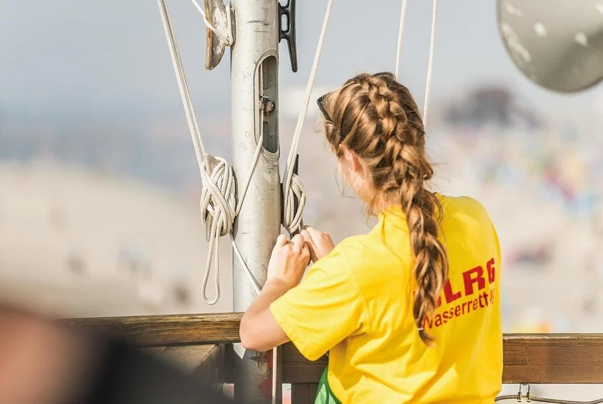 Frau der DLRG sichert die gehisste Fahne