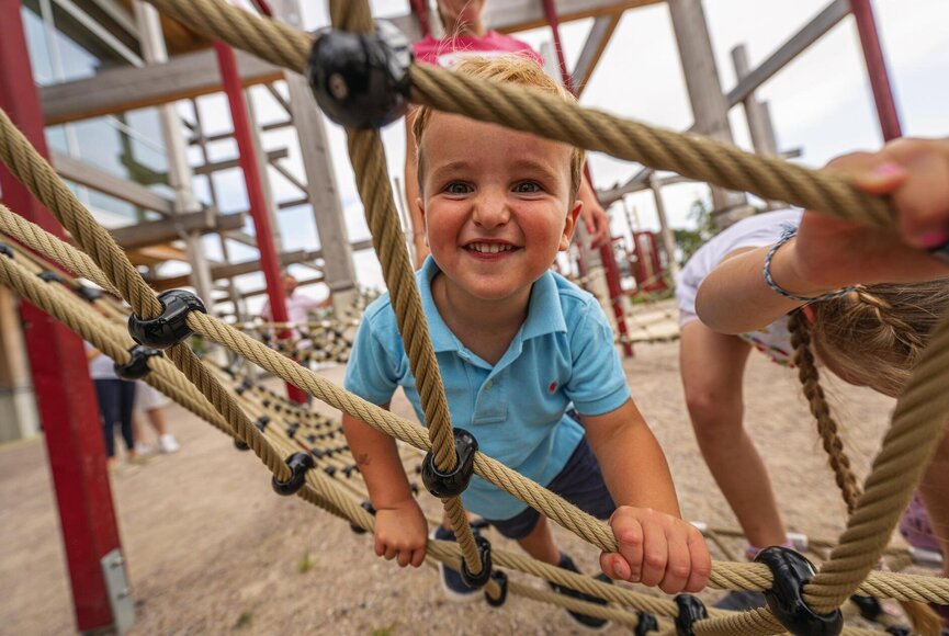 Junge beim Klettern auf dem Outdoor-Spielplatz des Erlebnis-Hus