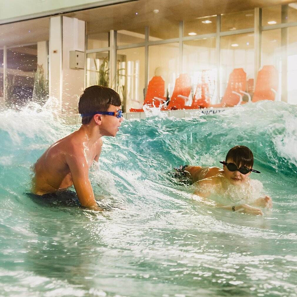 Kinder spielen im Wellenbecken