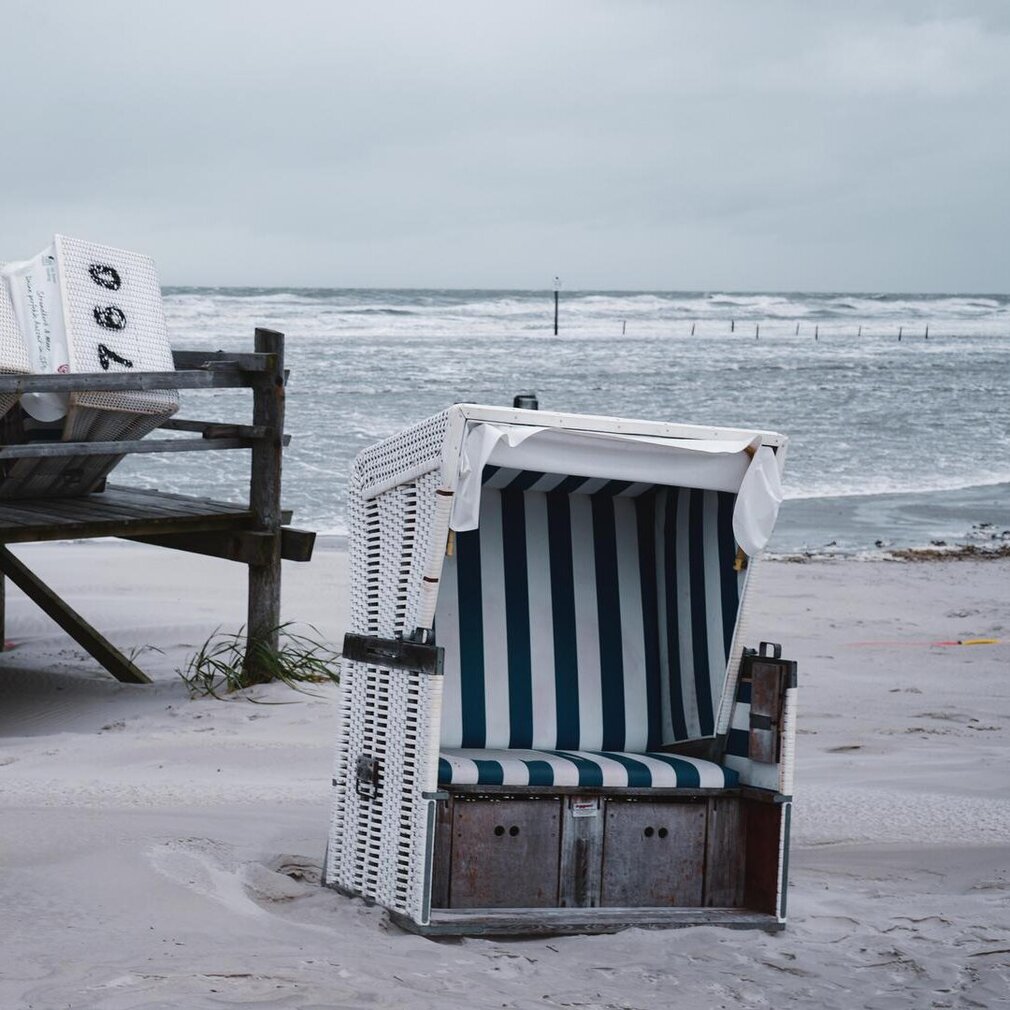 Strandkorb im Sand vor den Wellen der Sturmflut