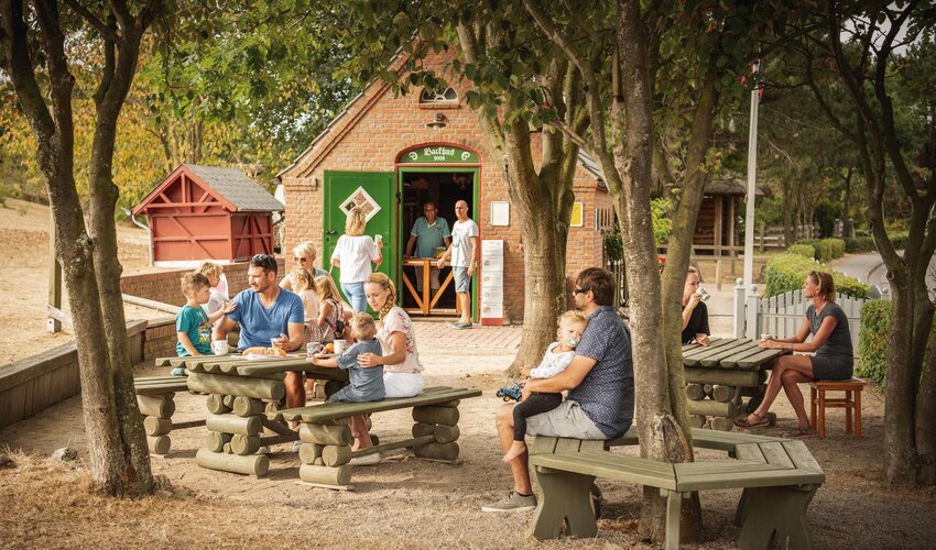 Besucher auf dem Sitzgelegenheiten der historischen Insel mit Backhus im Hintergrund