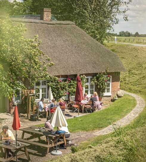 Reetdachhaus als Restaurant mit Personen von außen