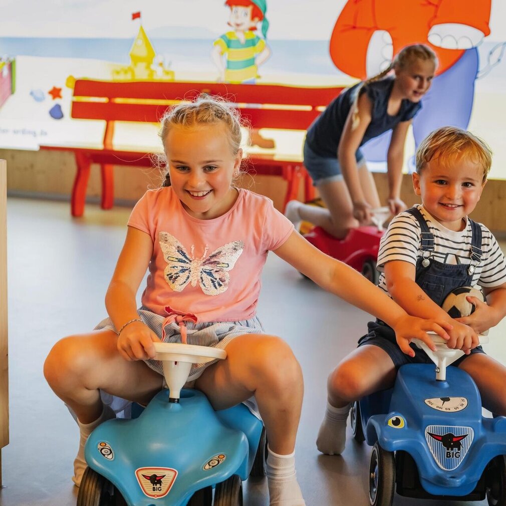 Kinder fahren auf Bobby-Cars durch das Spiele-Hus