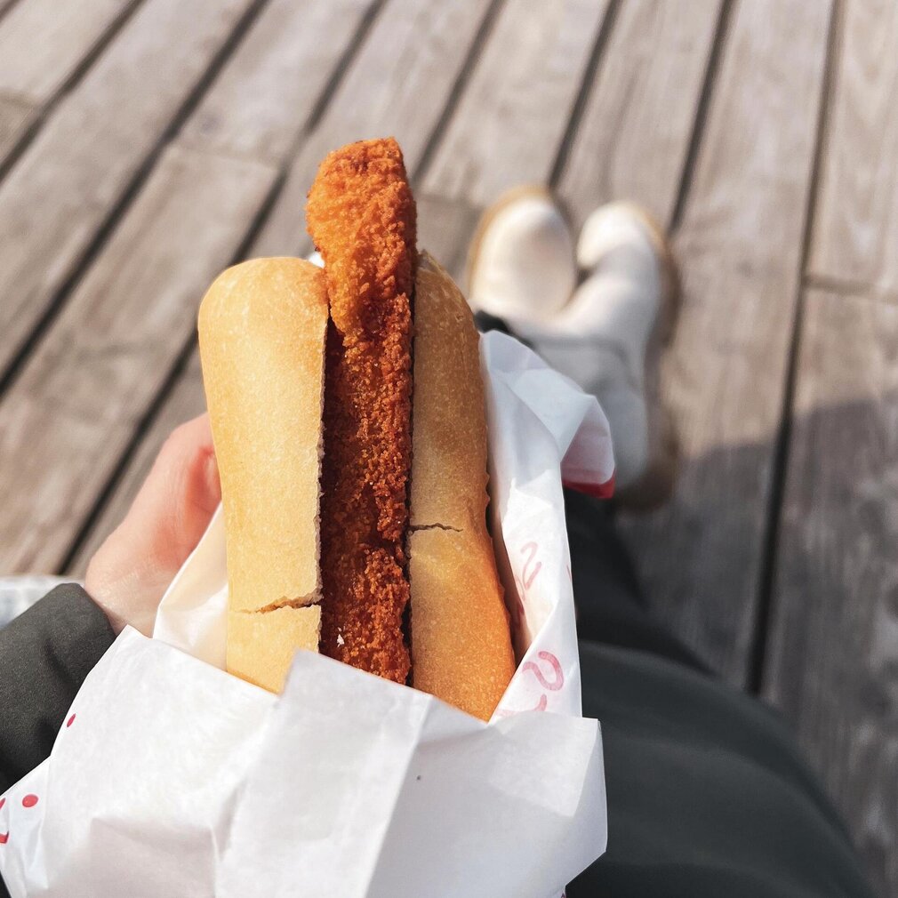 Hand hält Fischbrötchen auf dem Seebrückenvorplatz