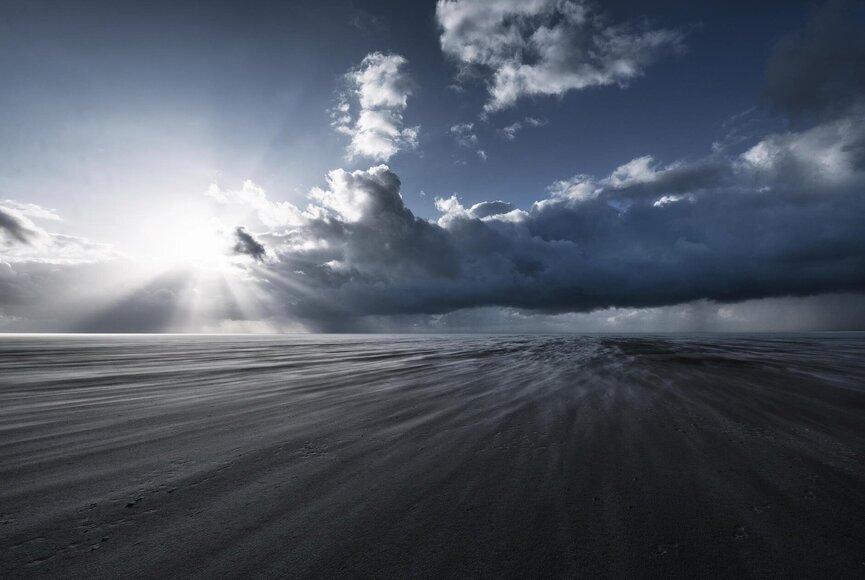 Sonnenstrahlen scheinen am Strand durch die dunklen Wolken
