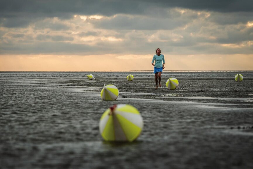 Jogger zwischen Bojen im Watt