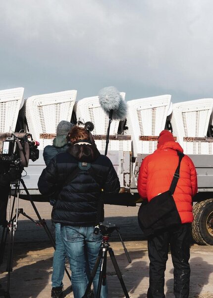 Filmteam vor einem Anhänger mit Strandkörben