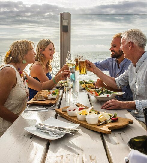 Freunde stoßen auf der Dachterrasse des Pfahlbaus miteinander an