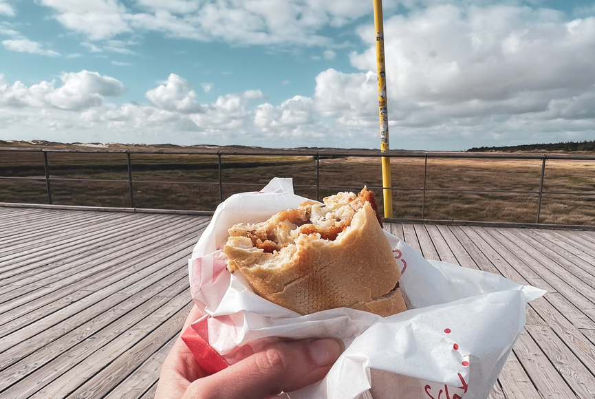 Hand hält ein Fischbrötchen auf dem Seebrückenvorplatz