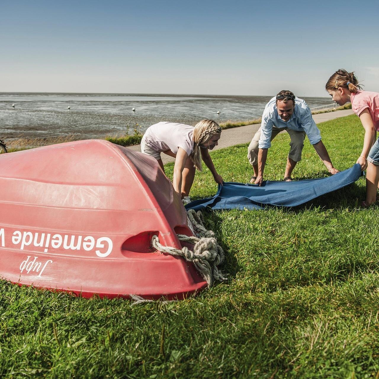 Familie breitet Decke an der Badestelle in Vollerwiek aus