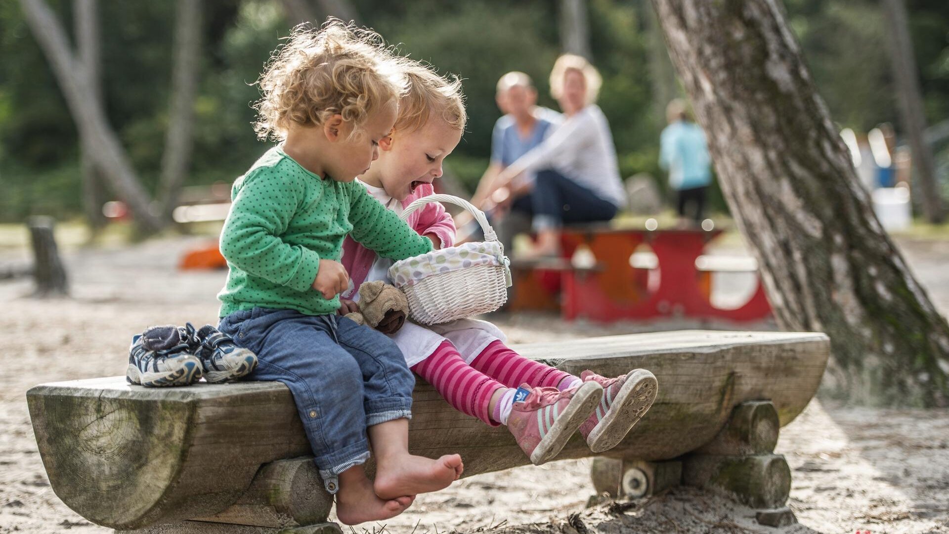 Kinder mit Osterkörbchen auf einer Bank auf dem Spielplatz