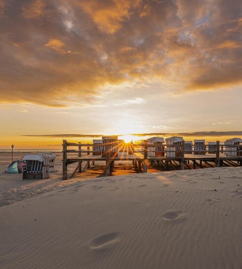 Strandkörbe auf einem Podest beim Sonnenuntergang